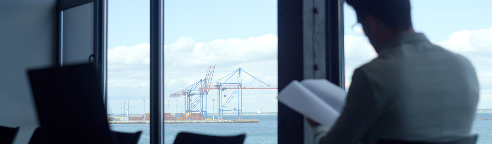 A man at his desk, with cranes in the distance outside