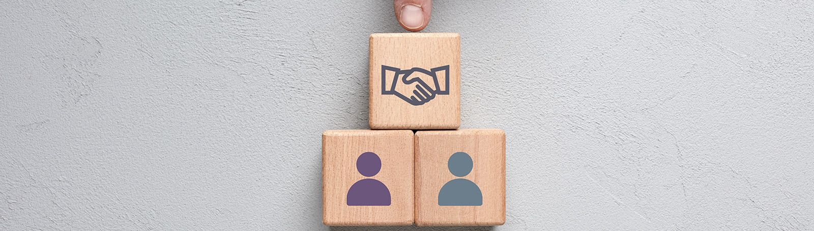 A graphic of two people icons on wooden blocks, with a mediator icon of shaking hands above