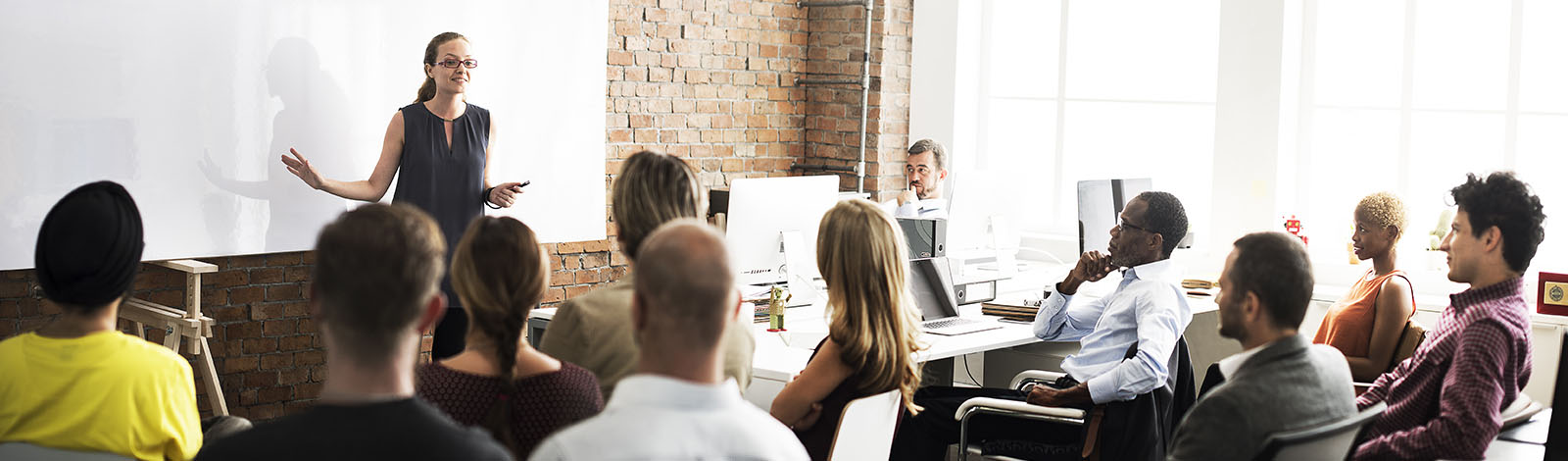 A woman leading a seminar, full class of people